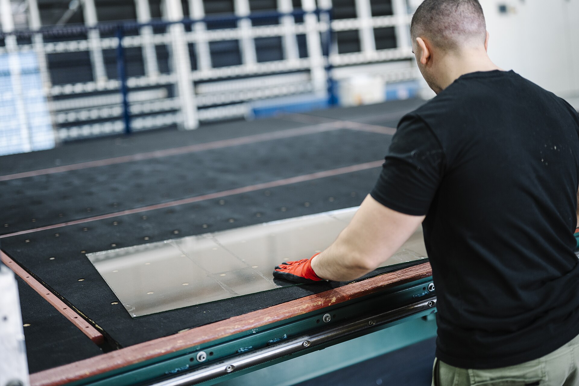 Production worker positioning sheet metal on an industrial worktable